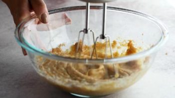 an electric mixer mixing cake batter in a glass bowl