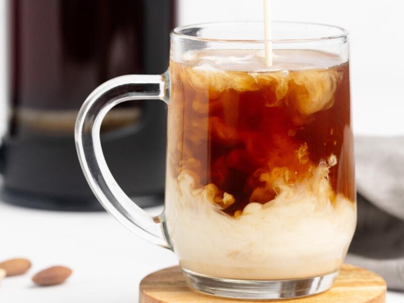 Keto coffee creamer swirling through a clear mug of freshly brewed hot coffee.