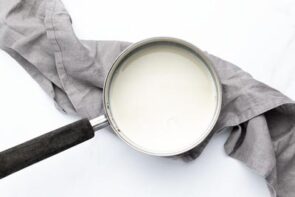 Heavy cream and almond milk heating gently in a saucepan to make homemade keto coffee creamer.