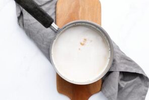 Sweetener and vanilla being stirred into the warm cream mixture to finish the keto coffee creamer.