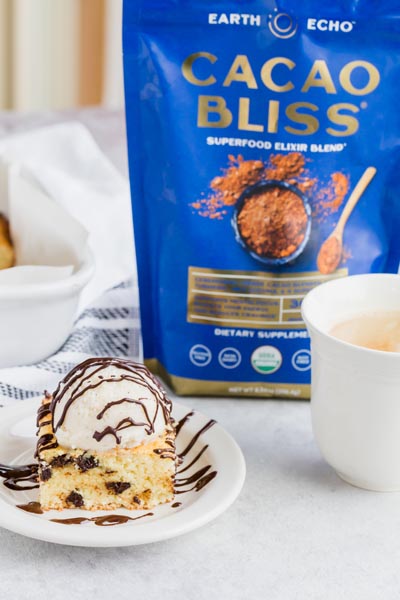 A chocolate chip cookie topped with ice cream next to a bag of Cacao Bliss and a cup of coffee.