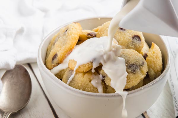 pouring cream on top a bowl of cookies