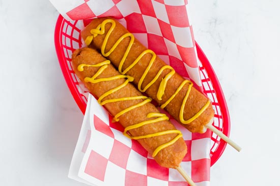 corn dogs in tray with mustard