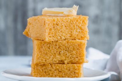 three keto cornbread slices stacked with butter on top