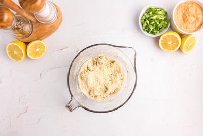 Almond flour sitting on top of crab meat in a measuring cup.
