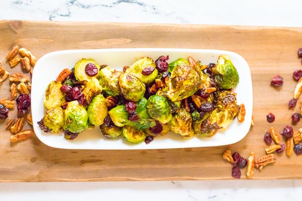 a tray of holiday brussels sprouts on a plater on a wooden board