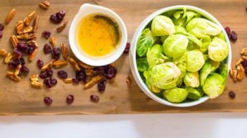 brussels sprouts and cranberries in a bowl with a sauce nearby