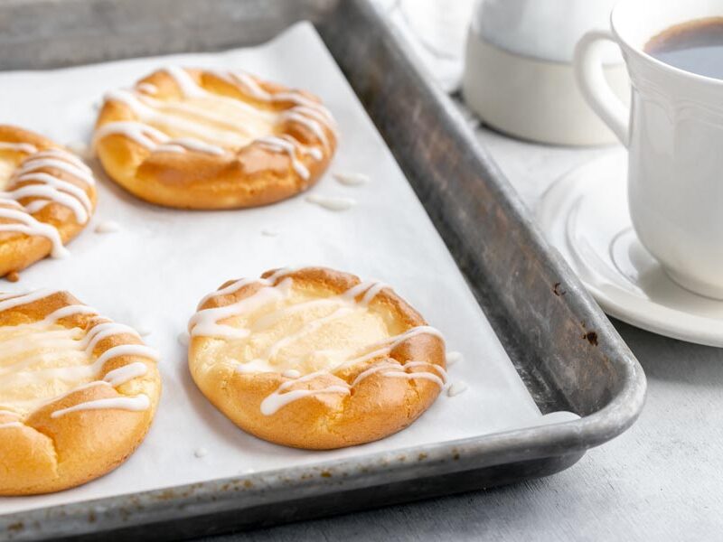 a baking sheet with four danishes next to a cup of coffee