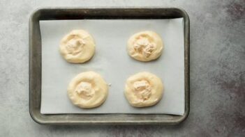 four unbaked danishes filled with cream cheese mixture on a baking sheet