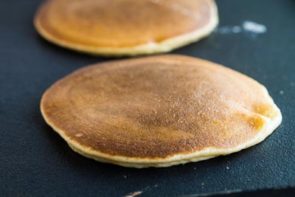 flipped keto pancakes cooking on a black griddle