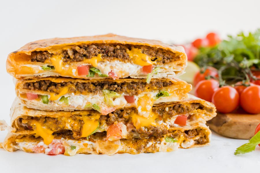 crunch wrap supremes from taco bell with lettuce, tomato, beef and cheese stacked up