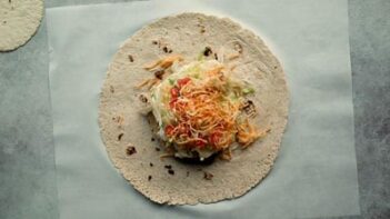 lettuce, tomato and shredded cheese in the center of a large tortilla