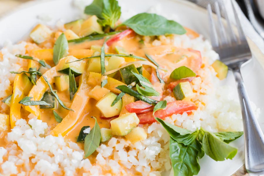 brightly colored curry dinner on a plate with a fork