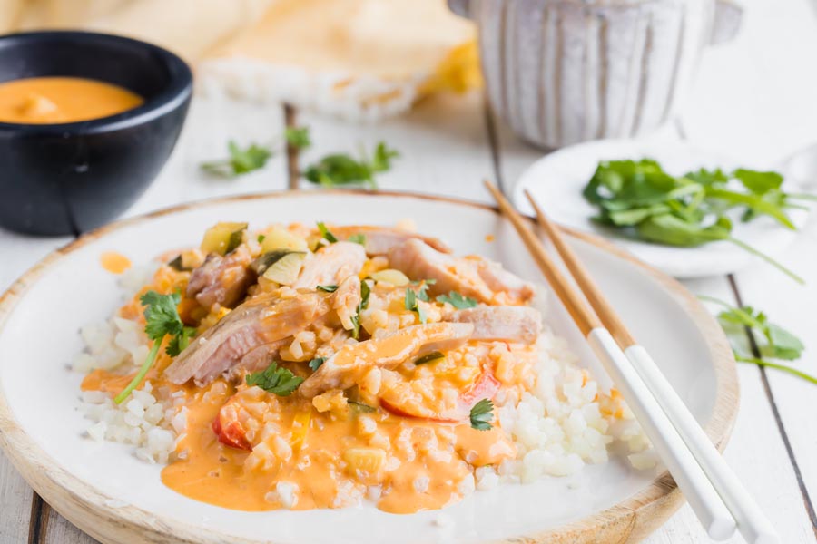 a plate of chicken curry over cauliflower rice with chopsticks