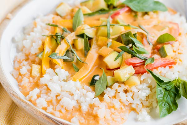 red curry sauce over a bed of cauliflower rice and brightly colored vegetables