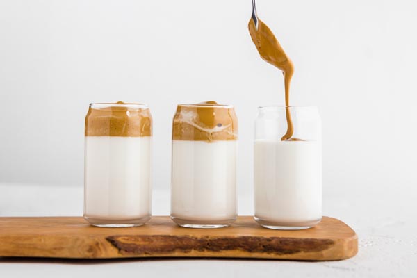 spooning whipped coffee layer onto cold glasses of nut milk