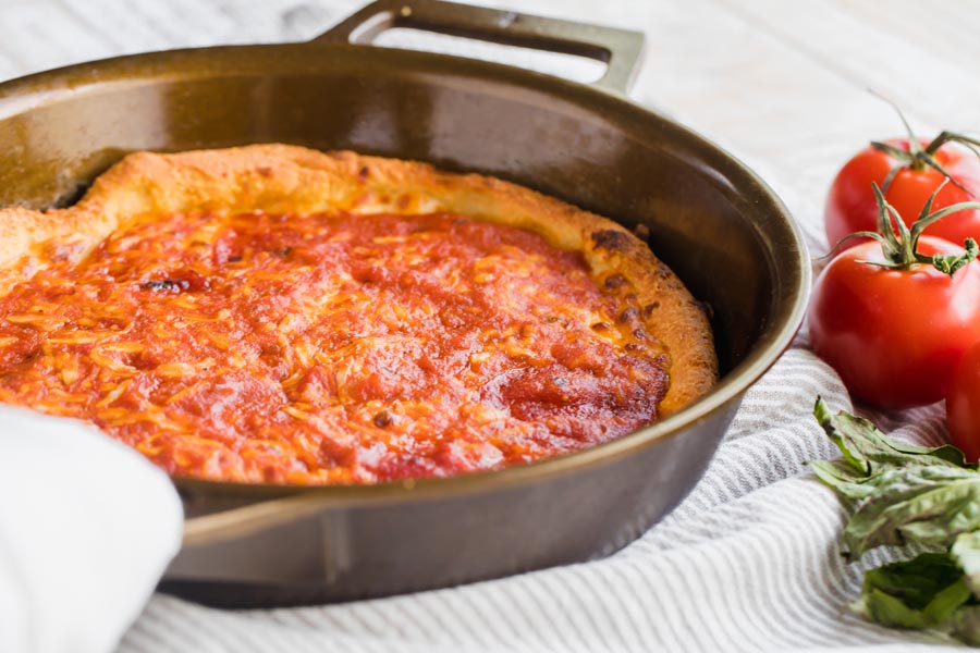 baked thick crust pizza in a skillet with red tomato sauce