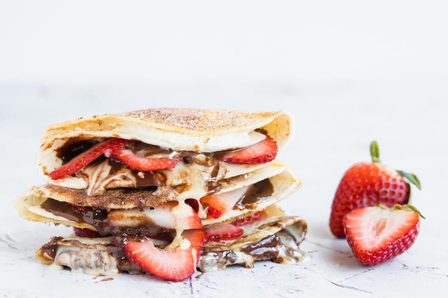 a stack of dessert wraps with sliced strawberries around and inside