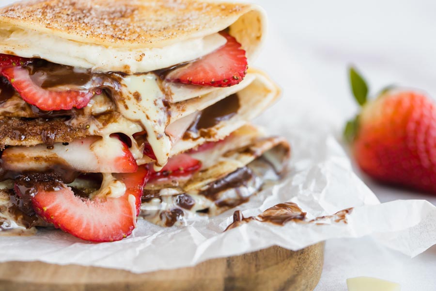 strawberries stuffed in a tortilla dessert with dripping chocolate and cream