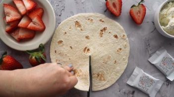 cutting a slit down the middle of a tortilla with scissors