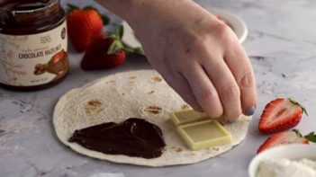 laying down white chocolate squares on a tortilla with nutella on it