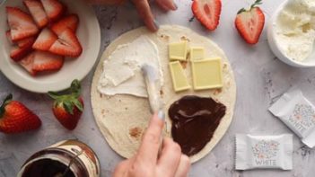 spreading cream cheese into the top quarter of a tortilla