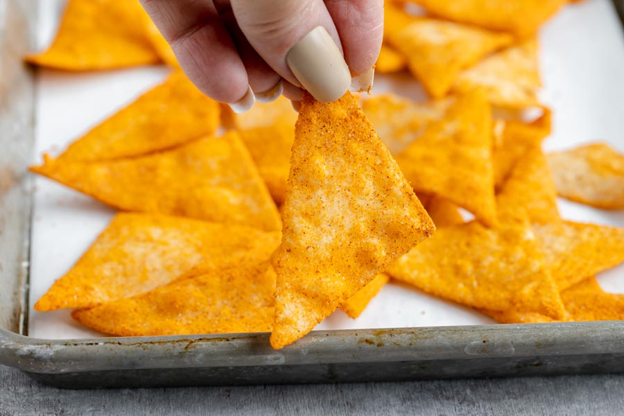 holding a homemade dorito chip in front of a tray of doritos