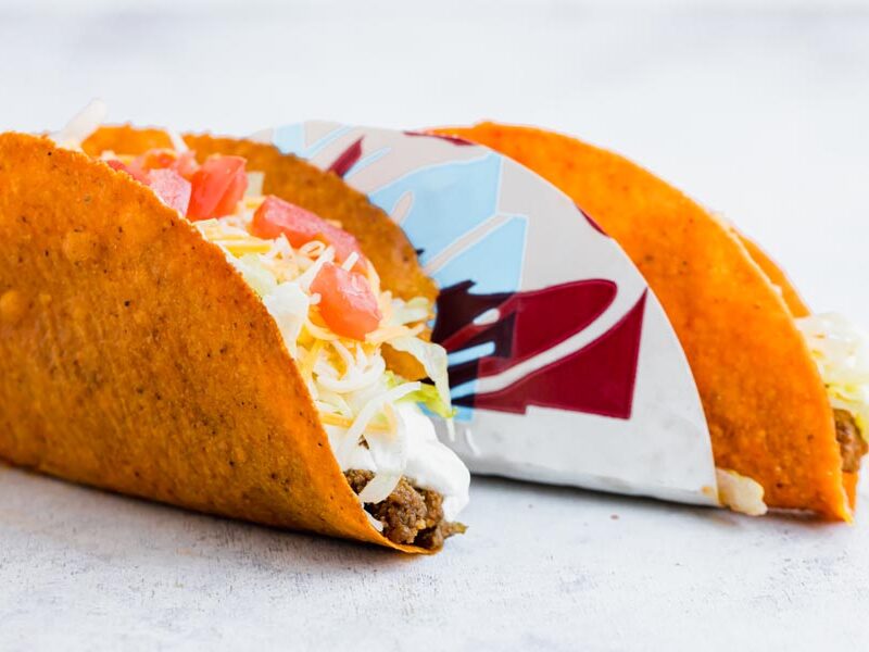 a taco bell doritos locos taco sits next to a homemade dortios locos taco
