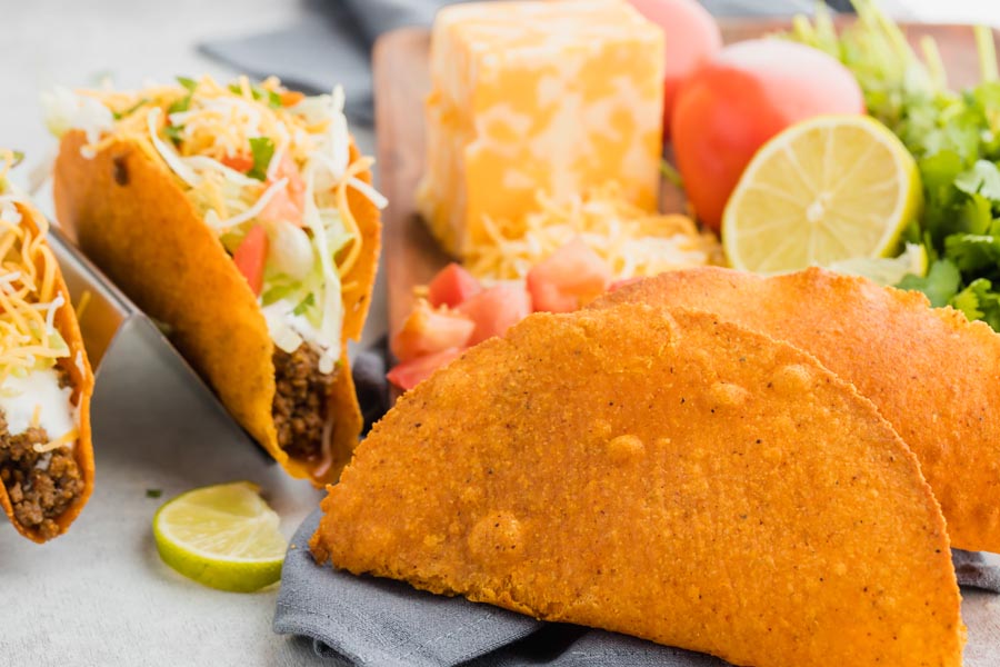 crispy Doritos flavored hard shell tacos in front of filled tacos and cheese