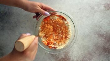 mixing taco shell ingredients in a bowl with a whisk that has a wooden handle