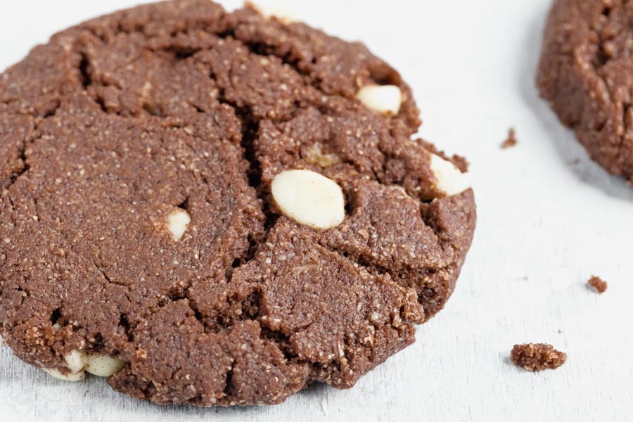 a large chocolate cookie with white chips inside next to crumbs