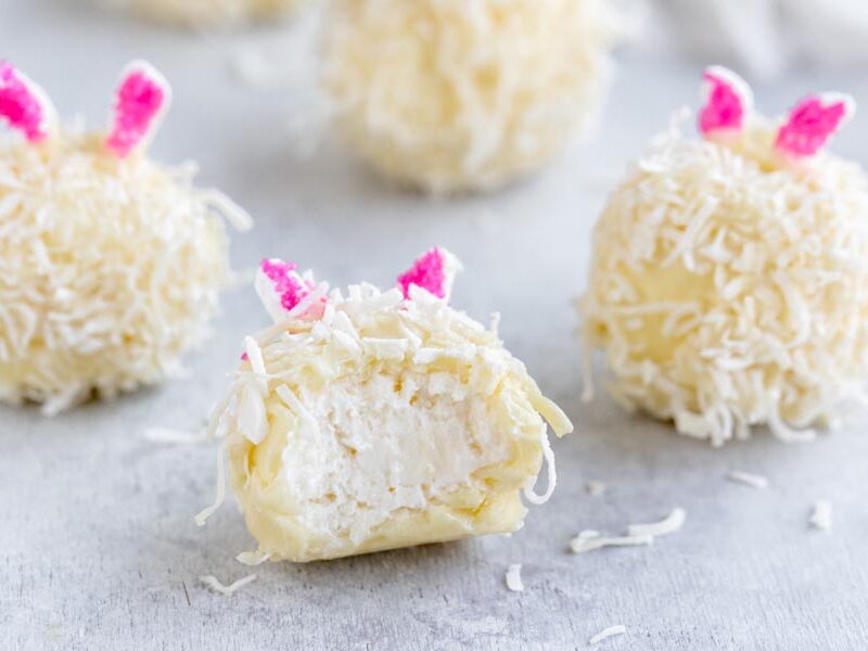 a bite taken out of a cheesecake ball that was covered in white chocolate and coconut