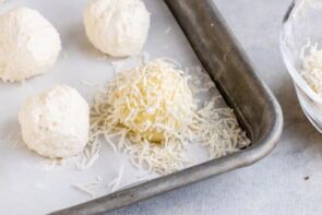 a cheesecake ball coated with shredded coconut on a baking tray