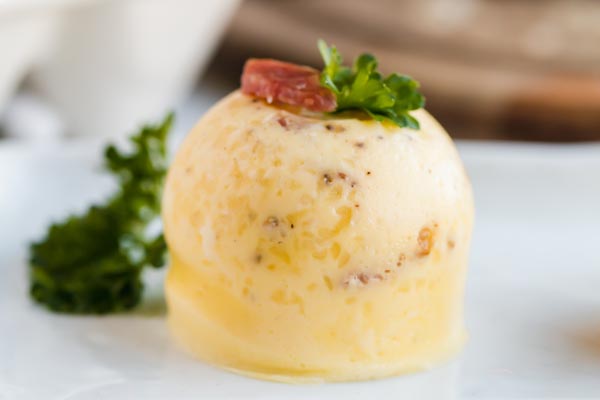 closeup picture of an egg bite topped with bacon and parsley