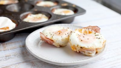 ham surrounds a baked egg on a small fluted plate