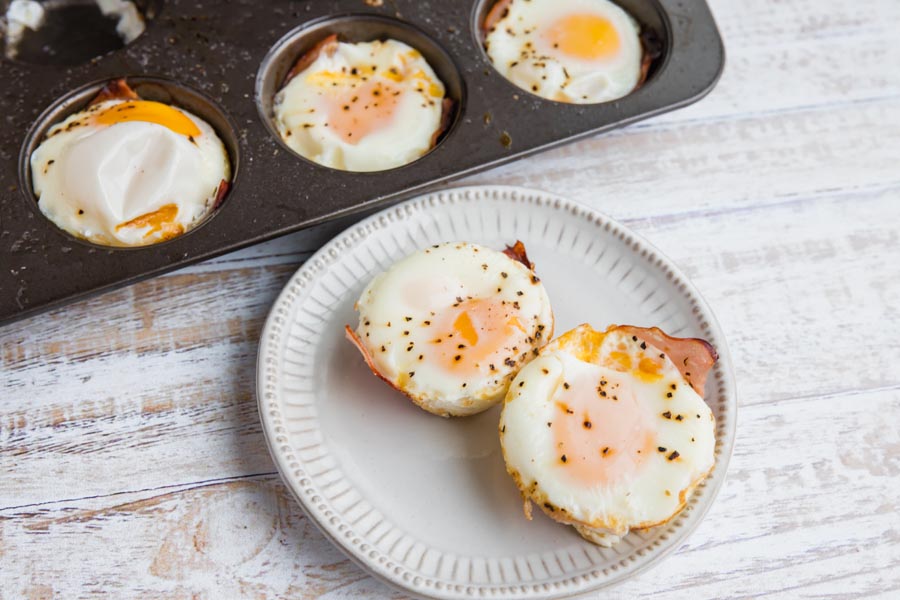 baked egg cups wrapped in ham with pepper sprinkled on top
