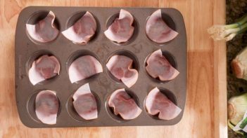 slices of deli ham inside the cavity of a muffin pan