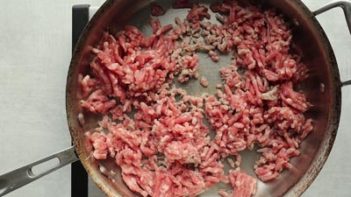 ground pork cooking in a stainless steal skillet