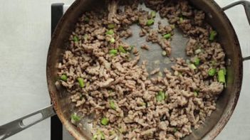 green onions and pork cooking in a skillet