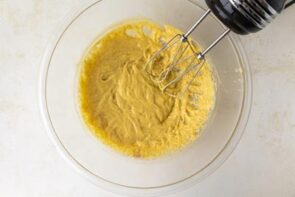 Eggnog pudding mixture being mixed with a hand mixer until thick and creamy.