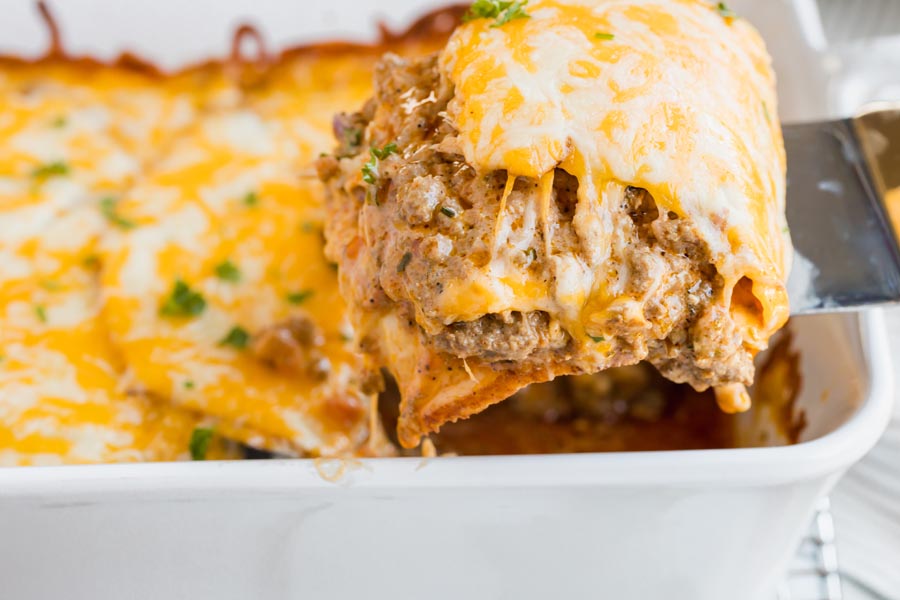 pull out a slice of enchilada casserole from the dish