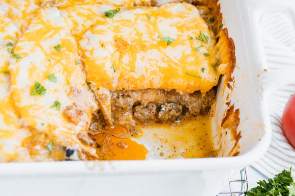 a portion of enchilada lasagna missing from the casserole pan