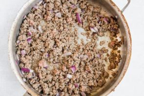 cooked ground beef and red onion in a skillet