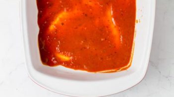 enchilada sauce covering the bottom of a 8 x 12 casserole dish
