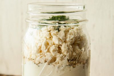 crumbled feta cheese on top a jar with creamy dressing in it