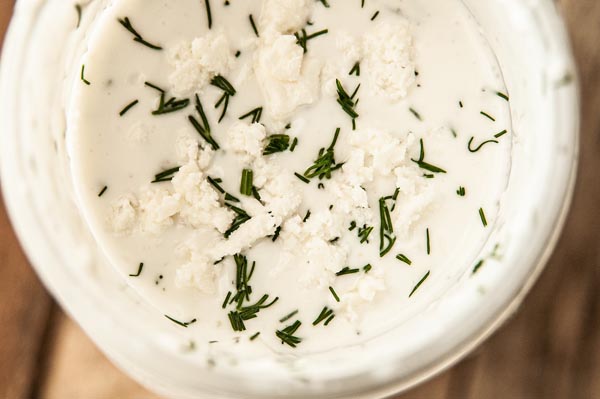 creamy salad dressing topped with dill and feta in a mason jar