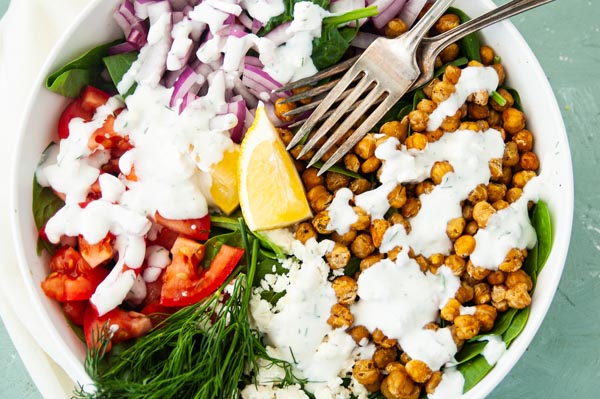 a colorful salad with tomato, dill and salad dressing on it