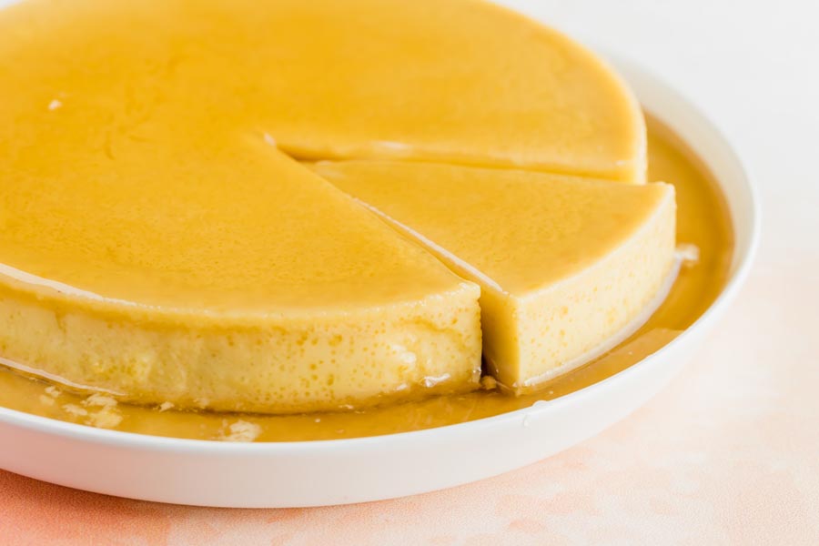 a slice partway out of a whole flan cake