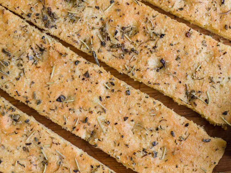 Crispy focaccia topped with herbs and oil with dimples on the top.