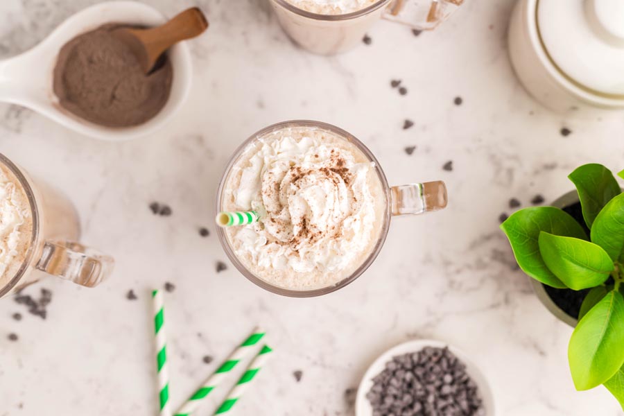 the top view of a whipped cream topped coffee drink with chocolate chips, cocoa and straws near